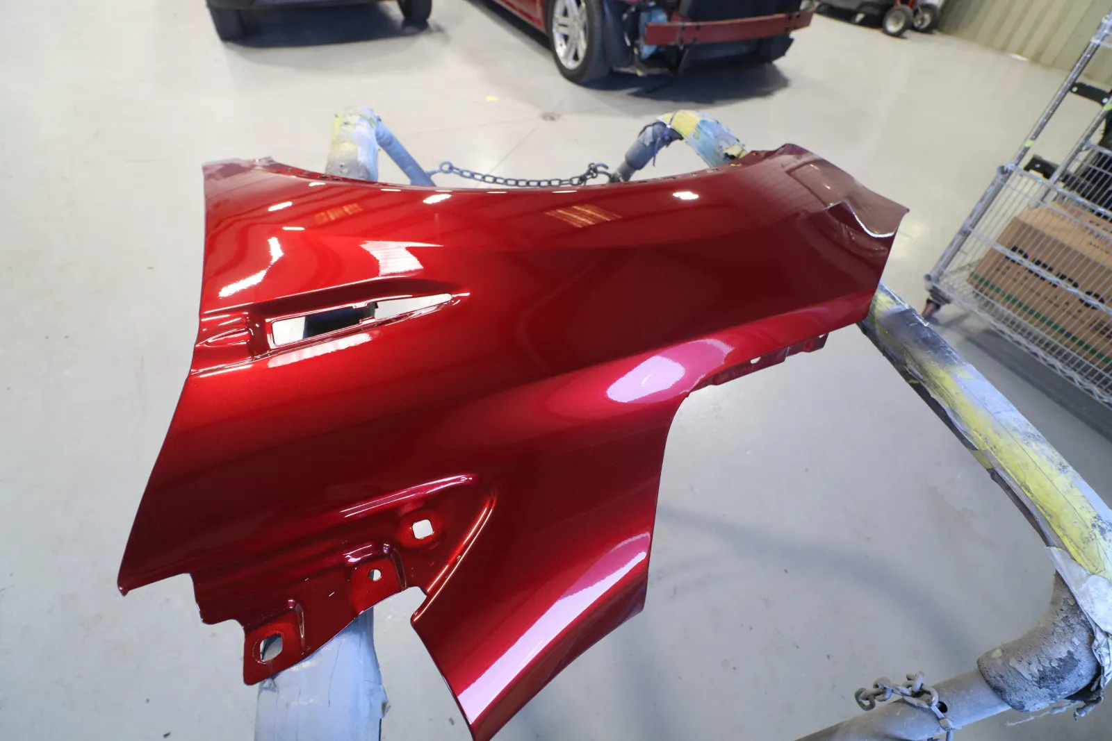 A red metallic painted quarter panel on a stand, perfectly color-matched and ready for assembly.